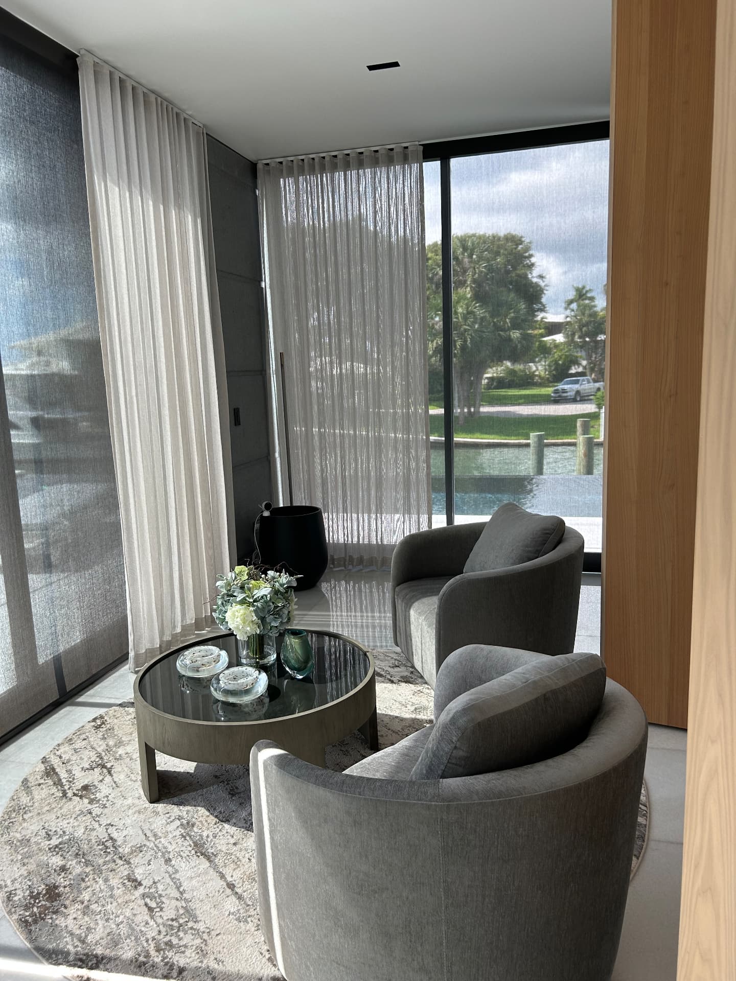Waterfront estate seating corner with sheer drapery and solar shades facing the pool